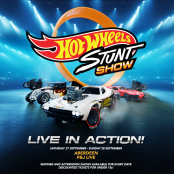 Some of the cars and bikes used in the Hot Wheels Stunt Show sitting in an arena.